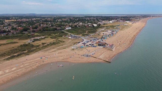 Aerial drone footage of Hayling Island Beach in Hampshire, England, capturing the long shingle shoreline, coastal waters, beach landscape, and surrounding coastline on a hot summer day.
