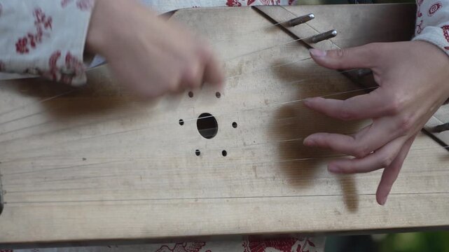 Hands playing gusli traditional Russian instrument, close-up