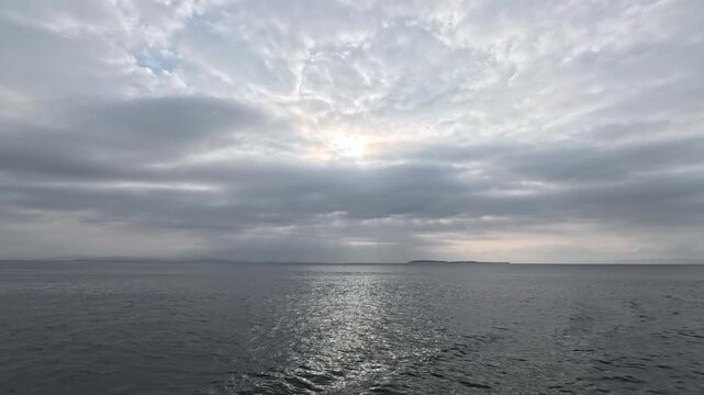 Beautiful crepuscular rays over the ocean with a distant island and a touch of blue sky on the left