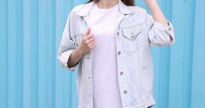 Woman wearing stylish white t-shirt near blue wall outdoors, closeup