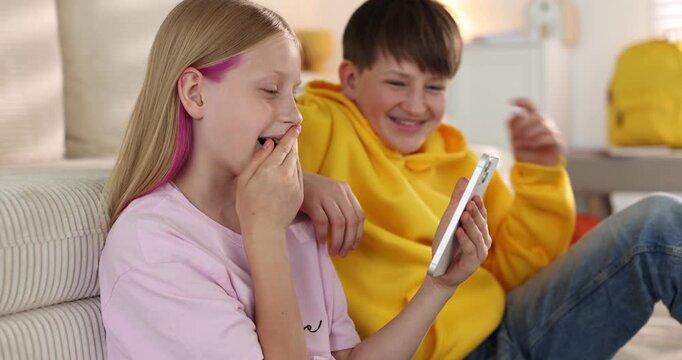 Brother and sister watching something on smartphone at home, camera moving in