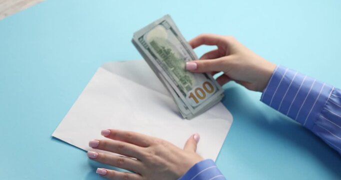 Bonus. Woman taking stack of dollar banknotes from envelope on light blue background, closeup