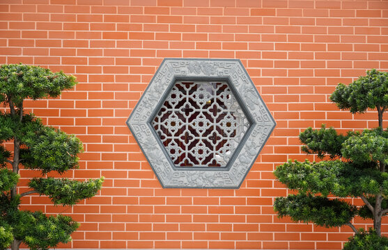 Traditional Chinese hexagonal window with intricate lattice on a brick wall