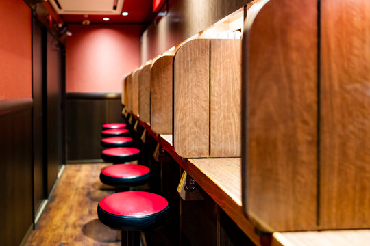 Interior of a traditional ramen restaurant with individual booths, wooden dividers, and stools, offering a private and cozy dining experience in Japan.