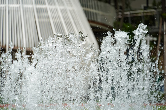 Dynamic water splashes frozen in motion against a blurred modern architectural background