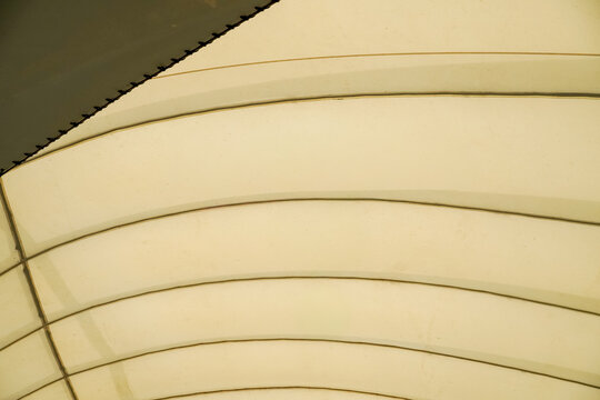 Abstract pattern of curved lines on a light yellow fabric surface
