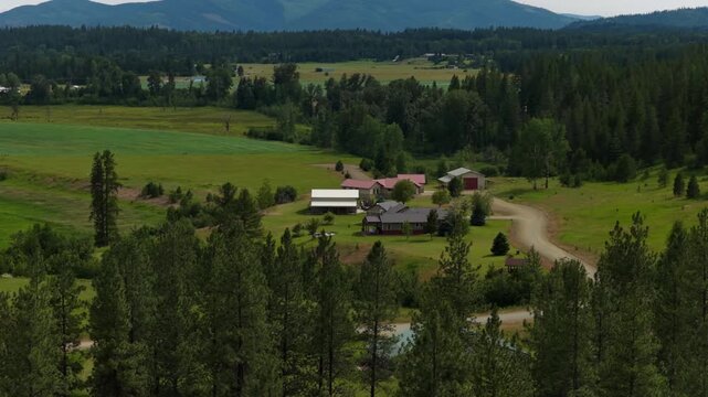Aerial of rural ranch property in the Idaho Panhandle in Bonner County in summer with barns and lush green grasslands