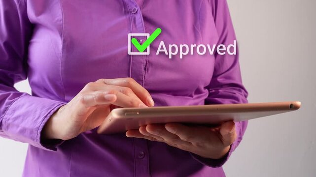 Close-up of a businesswoman interacting with her tablet with an animated checkmark and the word "approved"