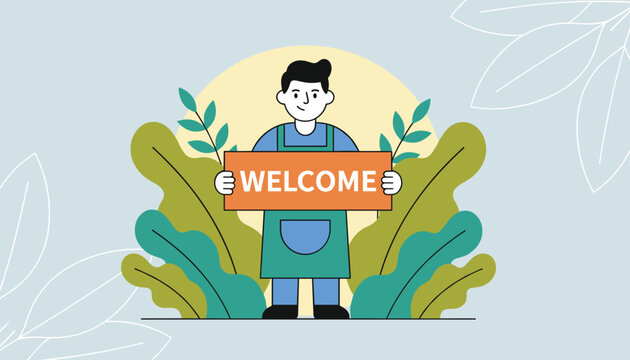 Friendly young male shopkeeper wearing an apron and holding an orange welcome sign in front of green leaves.
