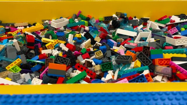 A pile of colorful plastic building blocks stored in a box. toys that foster a child's creativity. Close up video