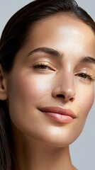 Fototapeta premium Close-up portrait of a young woman with glowing, healthy skin and natural makeup, bathed in soft light
