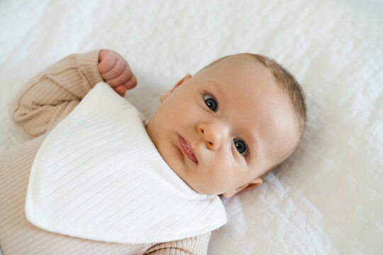 Portrait of a two to three month old baby with visible drool on lips. Natural process of infant development associated with increased saliva production in early infancy.