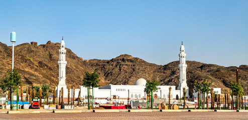 The white facade and minarets of Al Khandaq Mosque located at the base of the Jabal Sela mountains...