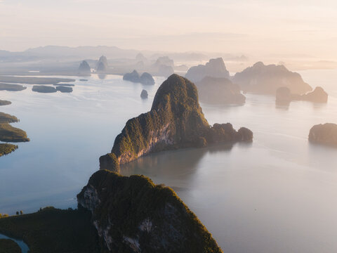 Aerial view of Samet Nangshe Viewpoint with limestone karsts rising from the calm waters of Phang Nga Bay under soft morning light in Tambon Khlong Khian, Chang Wat Phang-nga, Thailand.