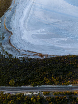 Aerial view of Pink Lake with its distinctive salt crust and surrounding native vegetation, bordered by a road in Esperance, Western Australia, Australia.