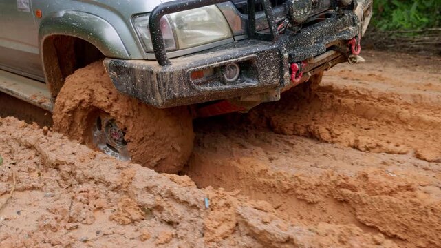 Action 4K slowmo of customized offroad tire spinning in heavy mud. Closeup shot of vehicle wheel forcing through difficult trail.