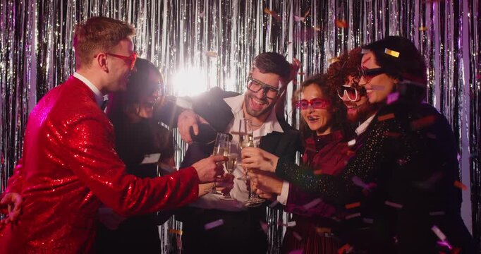 Happy group of friends drinking champagne from glasses and dancing at a evening party in a nightclub. Celebrate together, enjoying fun moments, music, and a vibrant social atmosphere.