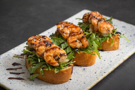 Shrimp on bread with salad and sauce served on a plate at a restaurant in the afternoon