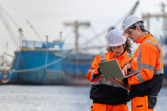 Logistics engineers using a laptop to coordinate operations at a shipping port, Port workers inspecting freight shipping, Team of marine logistics specialists managing shipping cargo at the harbor