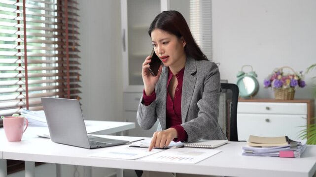 Stressed and angry asian businesswoman arguing during a difficult phone call, feeling frustrated with bad news, a customer complaint, or a work problem in her office