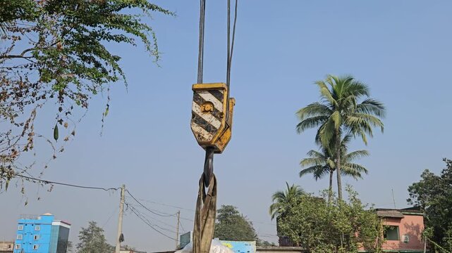 Mobile crane boom with heavy-duty lifting hook suspended against clear blue sky. Industrial lifting equipment, engineering machinery, infrastructure development, heavy construction