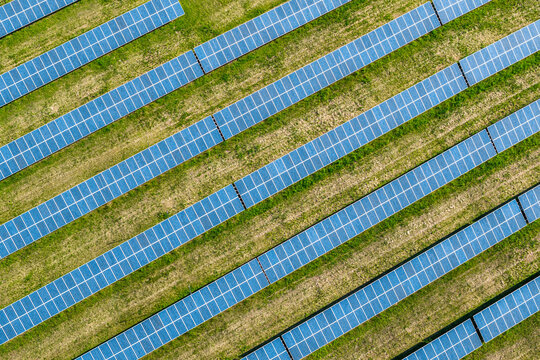 Aerial view of rows of solar panels arranged in a diagonal pattern over a green field in Kunkovice, Zlin Region, Czechia.