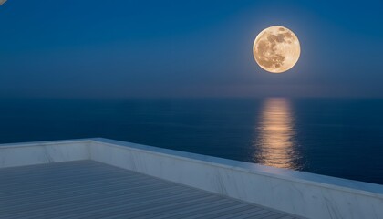 Naklejka premium Giant August full moon rising as a supermoon over a calm ocean with golden reflection, viewed from a modern luxury terrace for a peaceful celestial night concept