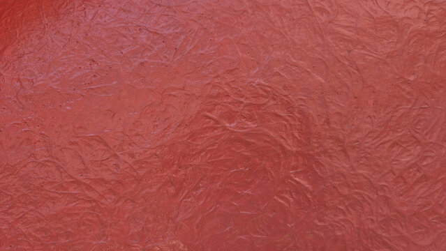 A close-up shot showing a textured, solid red surface with a chaotic, swirly, or fibrous pattern molded into it.
