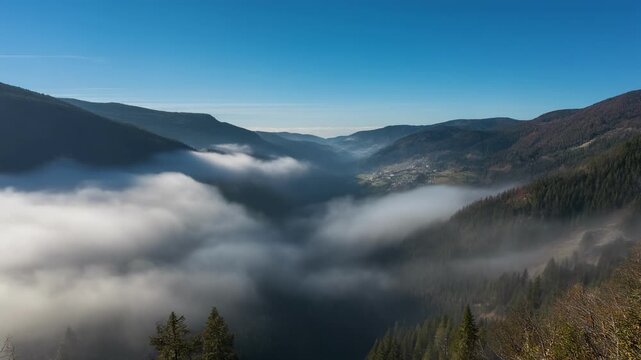 Mountain valley covered in thick fog under clear blue sky