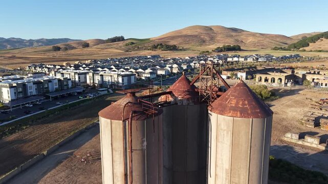 Aerial Over Rusted Grain Silos and Ruins at Dusk, American Canyon California, 4K

Aerial drone view over rusted historic grain silos and old brick ruins beside a housing development in warm dusk li