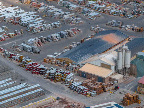 Aerial view of a large industrial storage yard filled with organized stacks of construction materials, bricks, and concrete blocks in Otnice, South Moravian Region, Czechia.