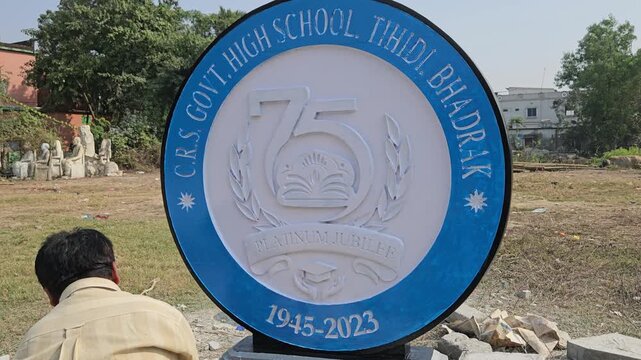Authentic footage of an Indian stone sculpture artist hand-painting a Platinum Jubilee commemorative school logo sculpture in Odisha, India. The video showcases traditional craftsmanship