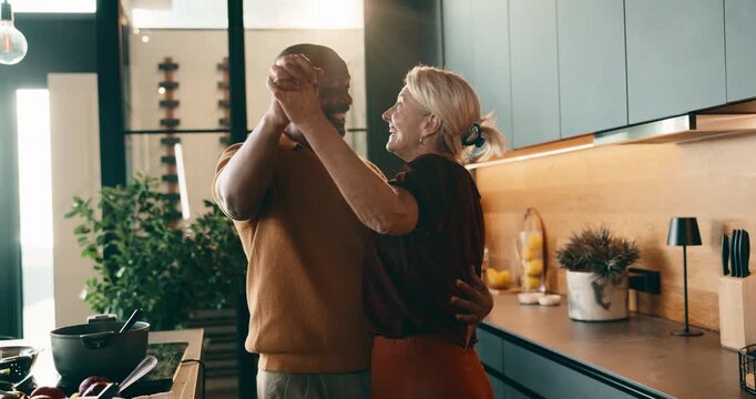 Dancing, cooking and couple in kitchen at house with music for bonding, love and connection. Happy, interracial people and mature man with woman for moving to romantic playlist with preparing meal.