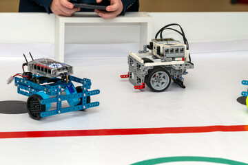 Blue metal chassis robot and plastic Lego robot facing each other on a track. Two different types of custom-made programmable robots (one with an aluminum blue frame, another made of blocks)  © ZeDesign