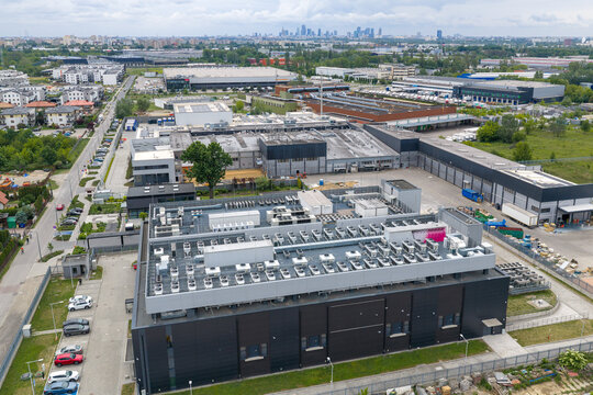 Aerial view of an AI data center with cooling units on the roof, surrounded by industrial buildings and urban infrastructure in Warsaw, Masovian Voivodeship, Poland.