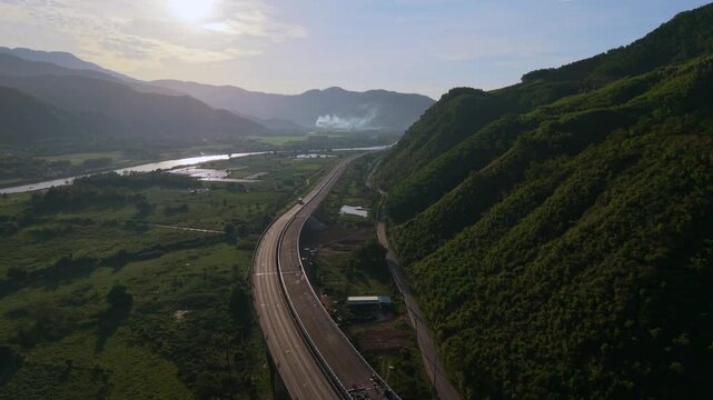 Cinematic drone footage of two winding mountain roads following a river through a lush valley in northern Vietnam. Scenic aerial landscape with dramatic natural beauty.