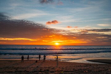 Stunning tropical beach sunset with glowing orange skies, gentle ocean waves, and peaceful island silhouettes creating a serene coastal atmosphere. © Narong Niemhom