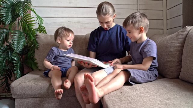 White parent reading family album with two white boys on sectional couch, feet relaxed, plant nearby, soft warm tones convey continuity, comfort, and passing down of stories as symbolic family ritual