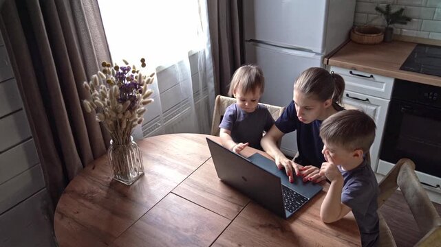 Parent watches over children engaged in learning. Mother supervises two sons as they study together cheerfully. Caregiver observes two boys working on homework at kitchen table during daylight