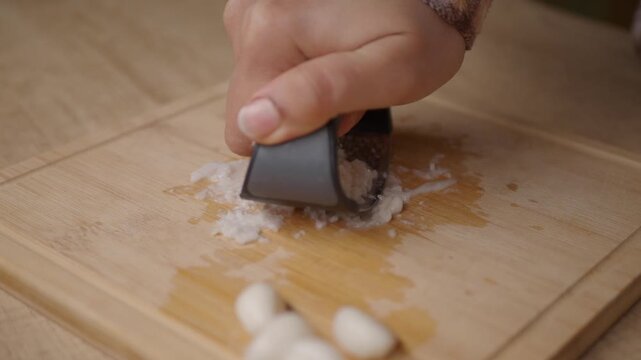 Cutting garlic on a wooden board with a tool