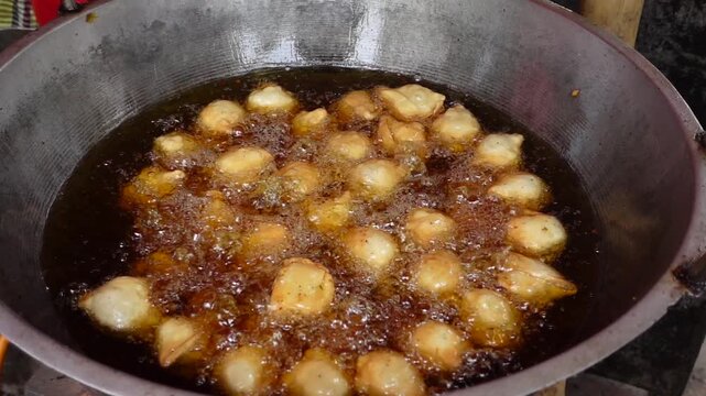 Frying indian traditional snacks singara in a street food stall
