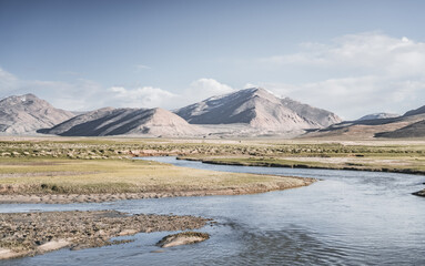 Clear-water rivers and lakes in a mountain valley, pastures and green grassy fields set against mountain ranges and snow-capped, glacier-clad peaks—a scenic landscape background © Denis