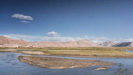 Clear-water rivers and lakes in a mountain valley, pastures and green grassy fields set against mountain ranges and snow-capped, glacier-clad peaks—a scenic landscape background © Denis