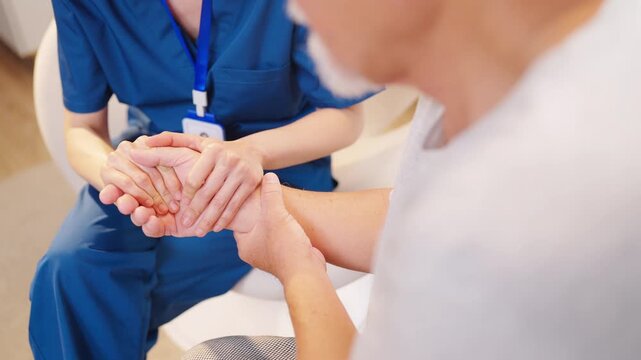 Compassionate caregiver holding elderly man hands offering emotional support comfort and reassurance during home healthcare visit promoting trust dignity mental wellbeing and quality senior care