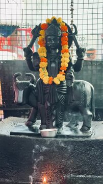 Lord Shani Dev adorned with vibrant flower garlands inside a Hindu temple. Revered as the deity of justice, discipline, karma, and righteousness, Shani Dev is worshipped for protection