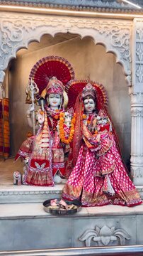 Lord Shiva and Goddess Parvati adorned with ornate traditional attire, floral garlands, and sacred jewelry inside a Hindu temple. The divine couple symbolizes eternal love, harmony, family values