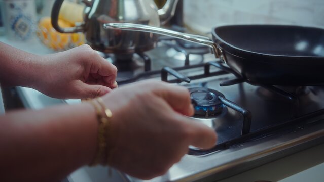 Turning on a Gas Stove Burner to Heat a Frying Pan in a Kitchen for Cooking
