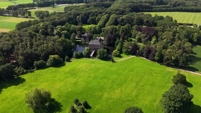 Aerial shot of an old castle surrounded by a moat and verdant forest