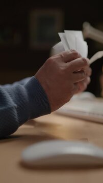 Paychecks. Close-up of hands holding checks and entering data into computer. Vertical video