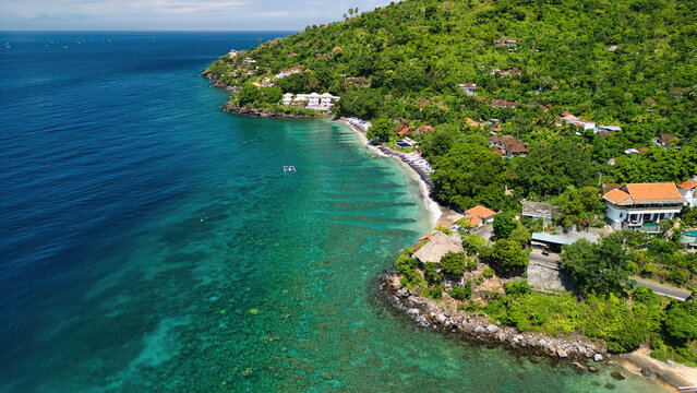 Aerial view of Bintang Beach Villa nestled along the lush green coastline with turquoise waters and rocky shores in Kecamatan Abang, Bali, Indonesia.